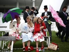 I festaioli di Epsom si riparano dalla pioggia e dal vento mentre le nuvole si accumulano nel giorno del Derby